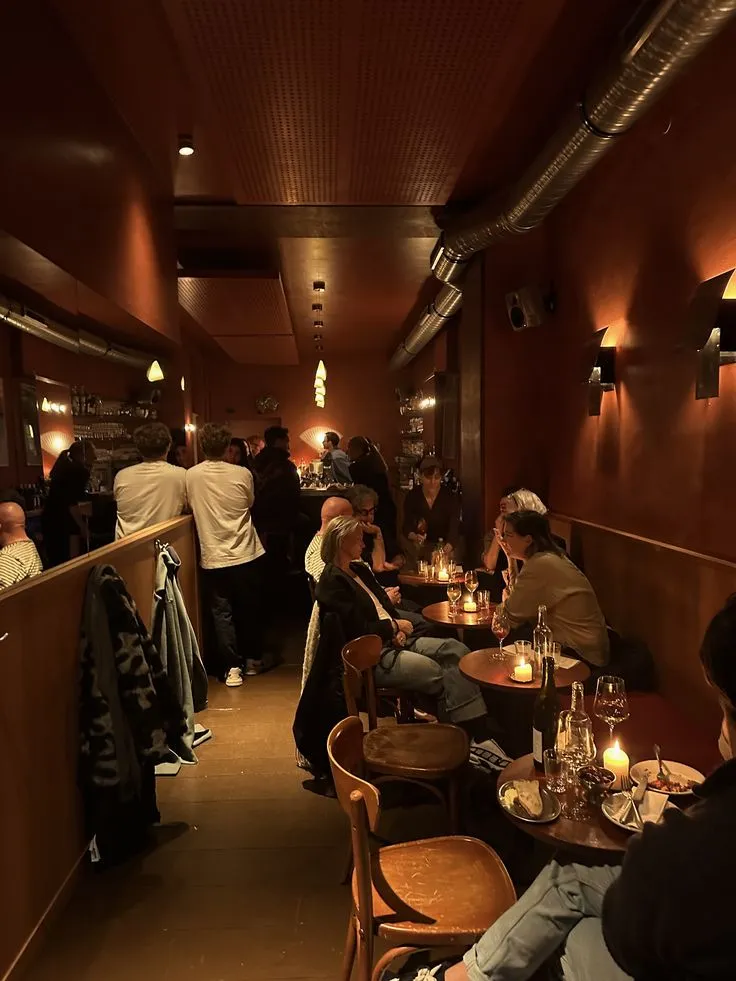 Volle Weinbar am Abend, warme Terrakotta-Wände, Kerzenlicht